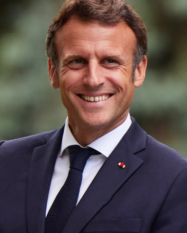 Photograph of Emmanuel Macron in a dark suit and blue tie.