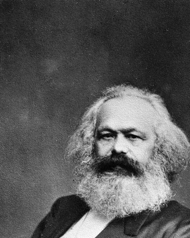 Photographic portrait of Karl Marx with full beard, seated in a dark suit.