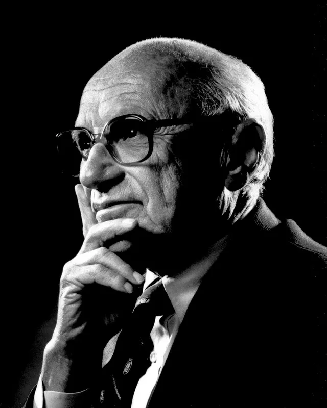 Photographic portrait of Milton Friedman wearing glasses and a suit, smiling slightly.