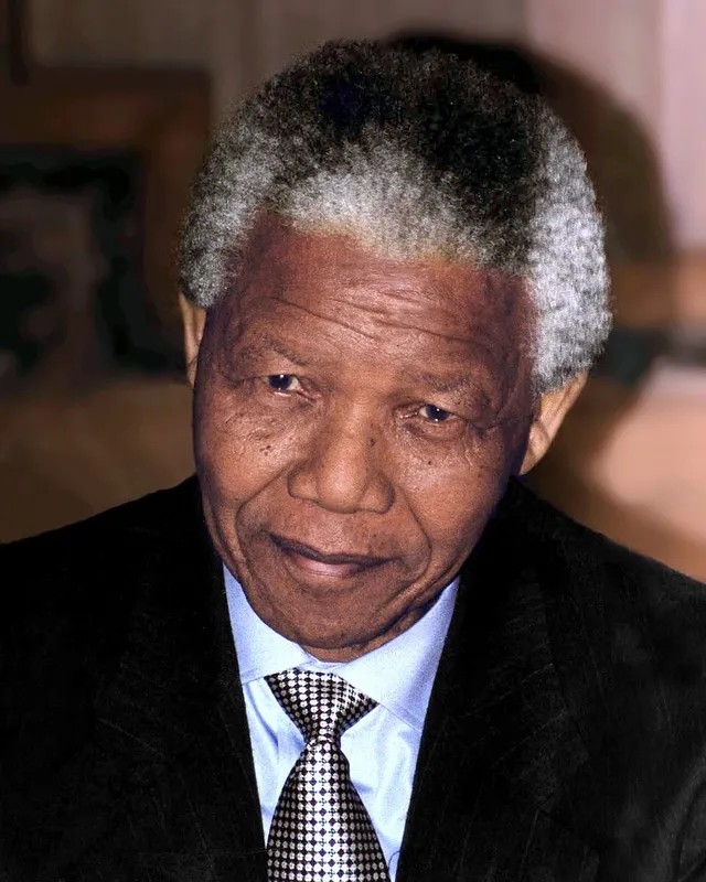 Photograph of Nelson Mandela in 1994, smiling, in a patterned shirt.