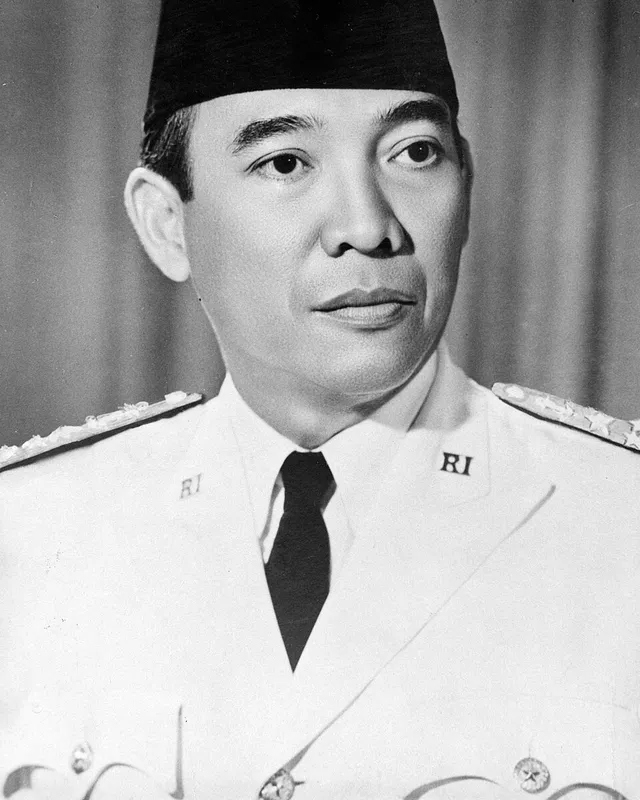 Photographic portrait of Sukarno in a white uniform and peci cap.