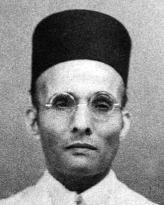 Photographic portrait of V. D. Savarkar in a white jacket and cap.